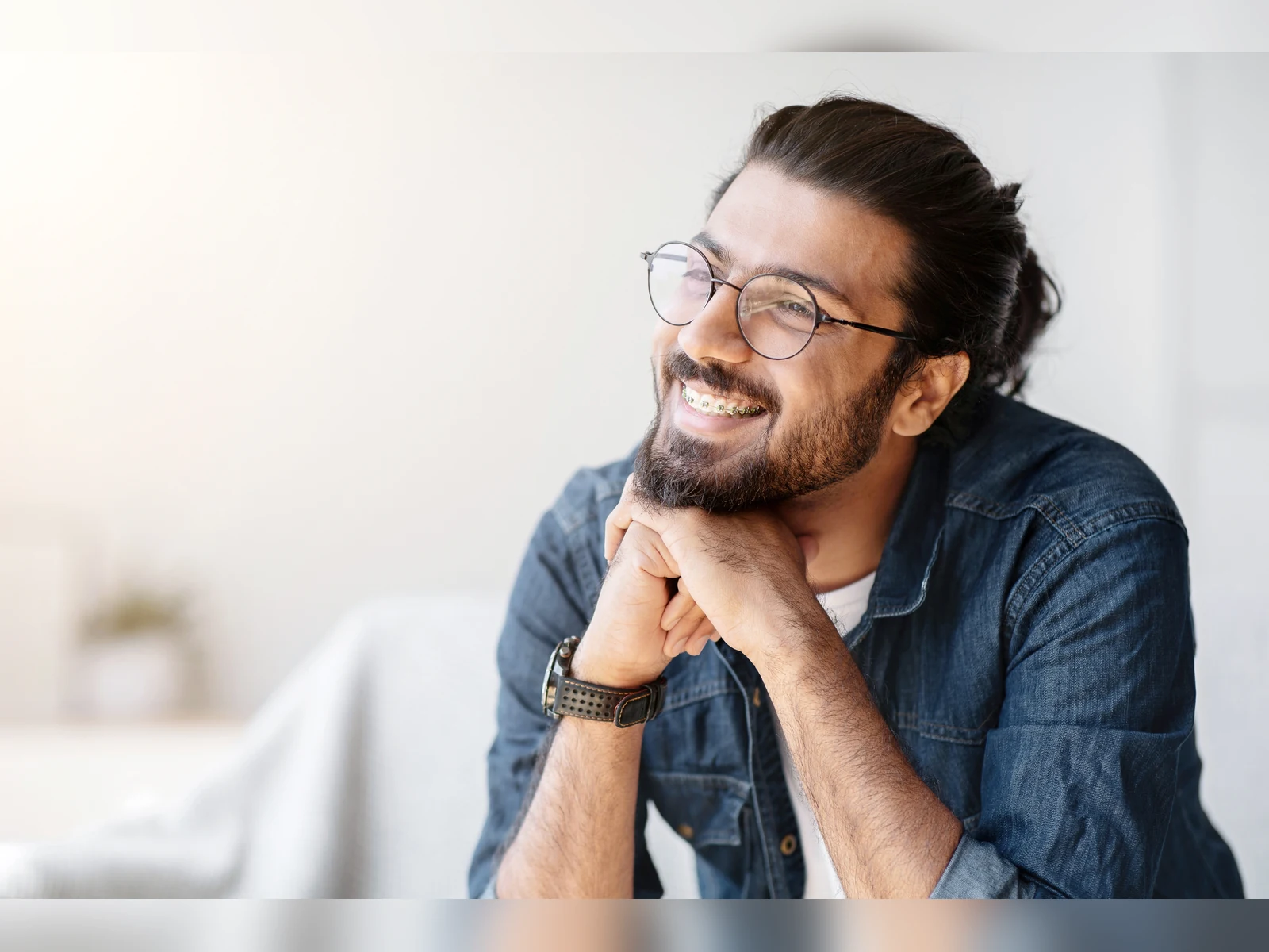 An adult orthodontic patient smiling in a bright modern setting