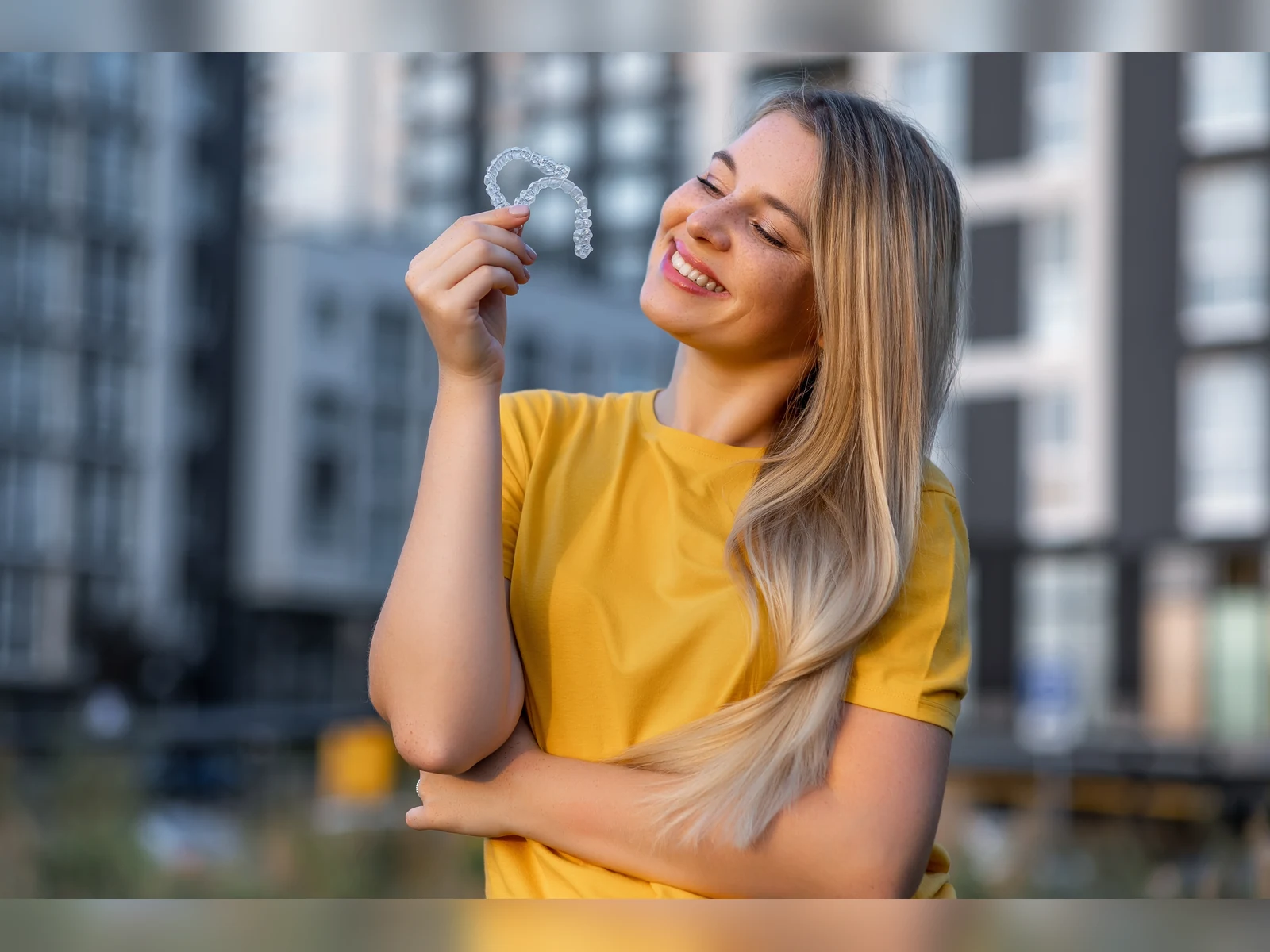 A smiling patient holding clear aligners