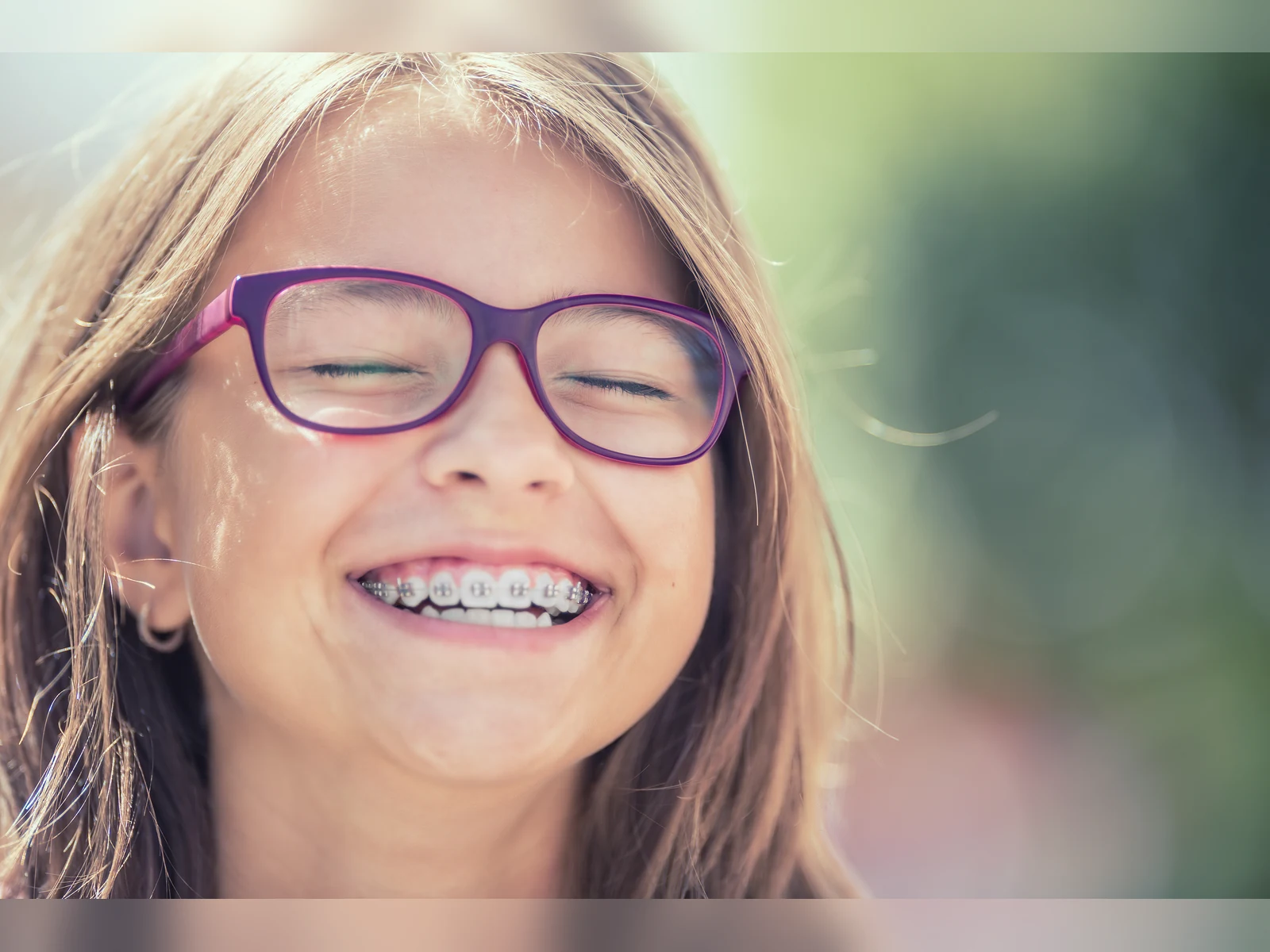 A child with purple glasses smiling with braces