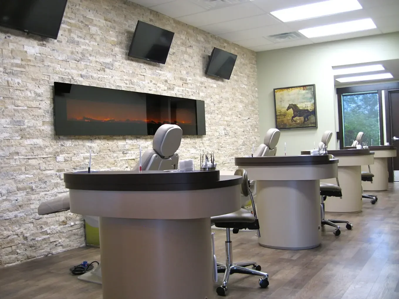 Open treatment bay at McKay Orthodontics with televisions and a linear fireplace on a stone wall
