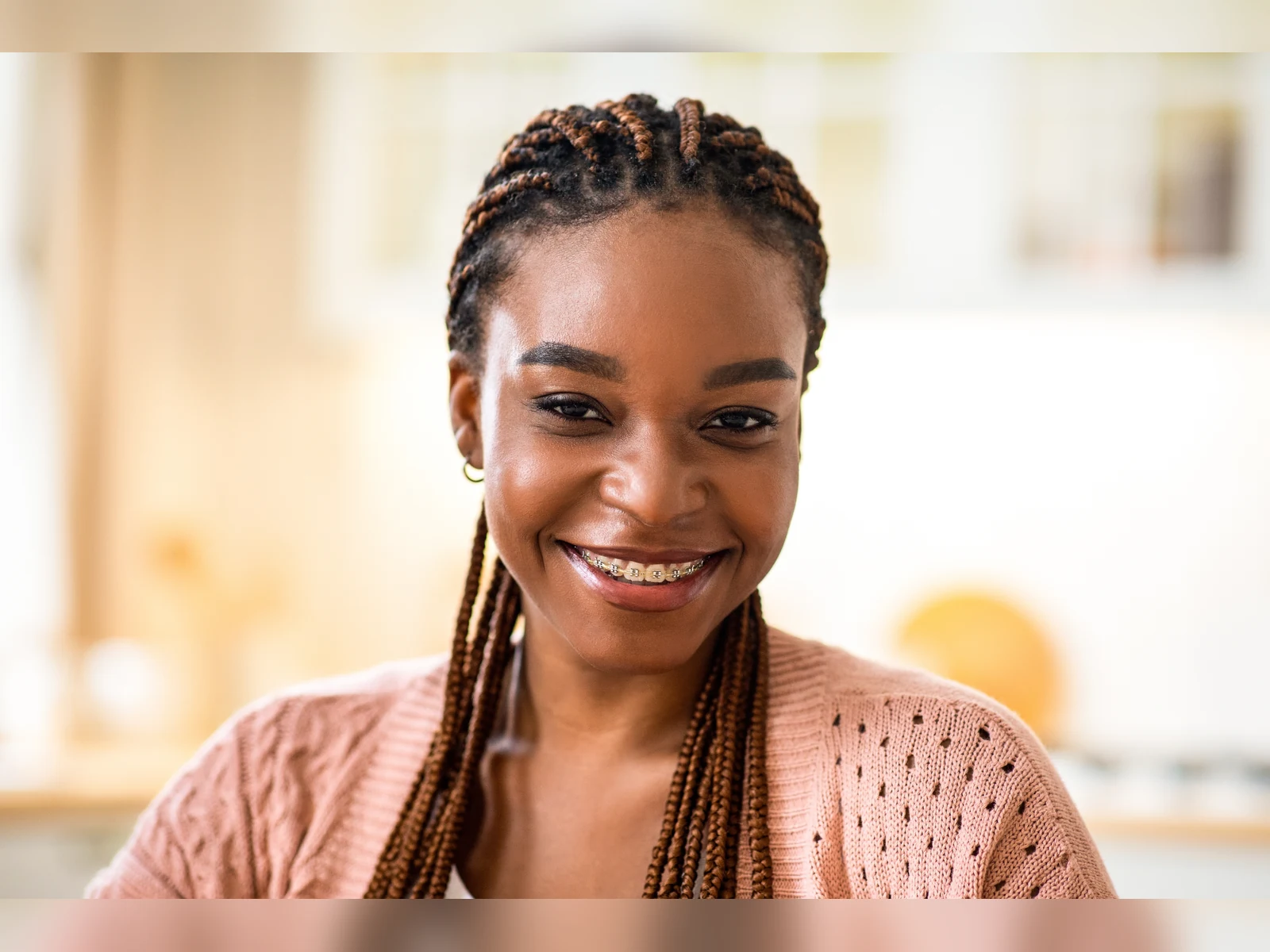 A smiling teen with braces centered in a warm portrait