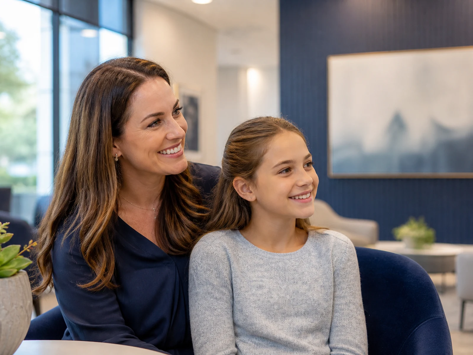 A parent and child smiling together in a welcoming orthodontic consultation area