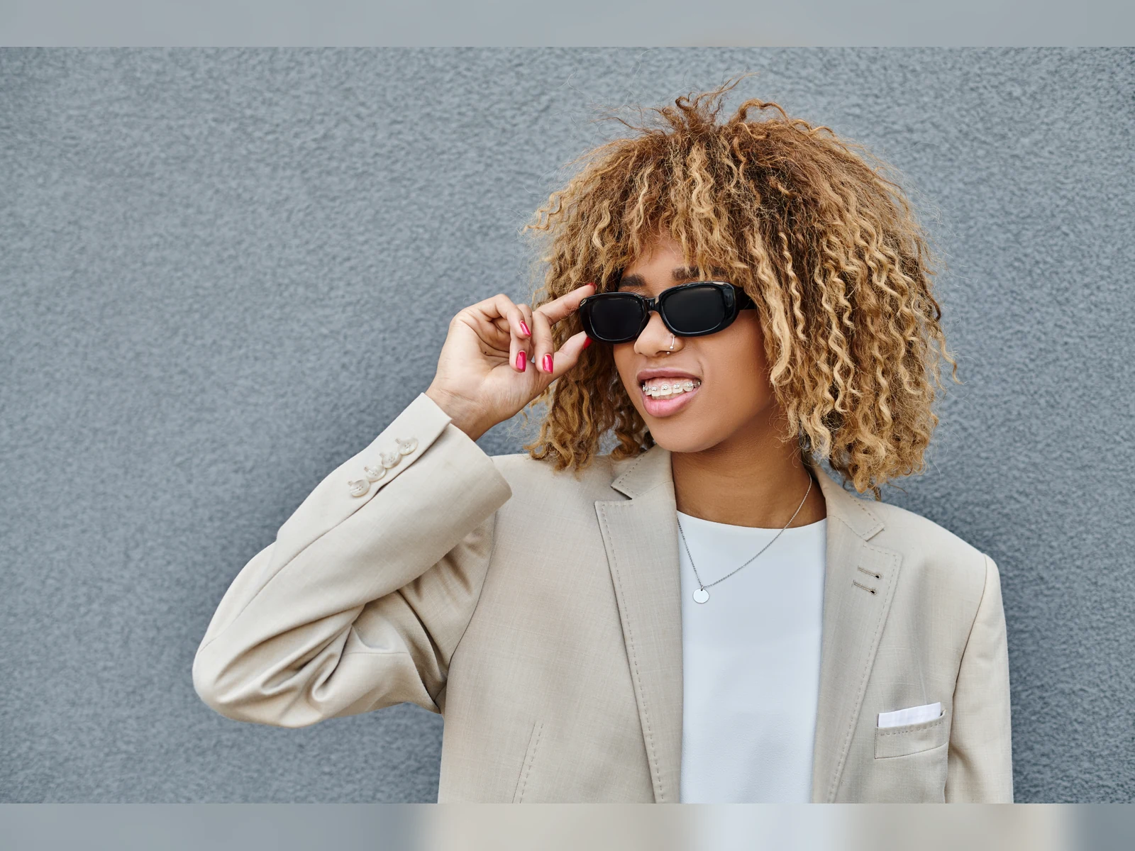 An adult patient with sunglasses smiling with braces