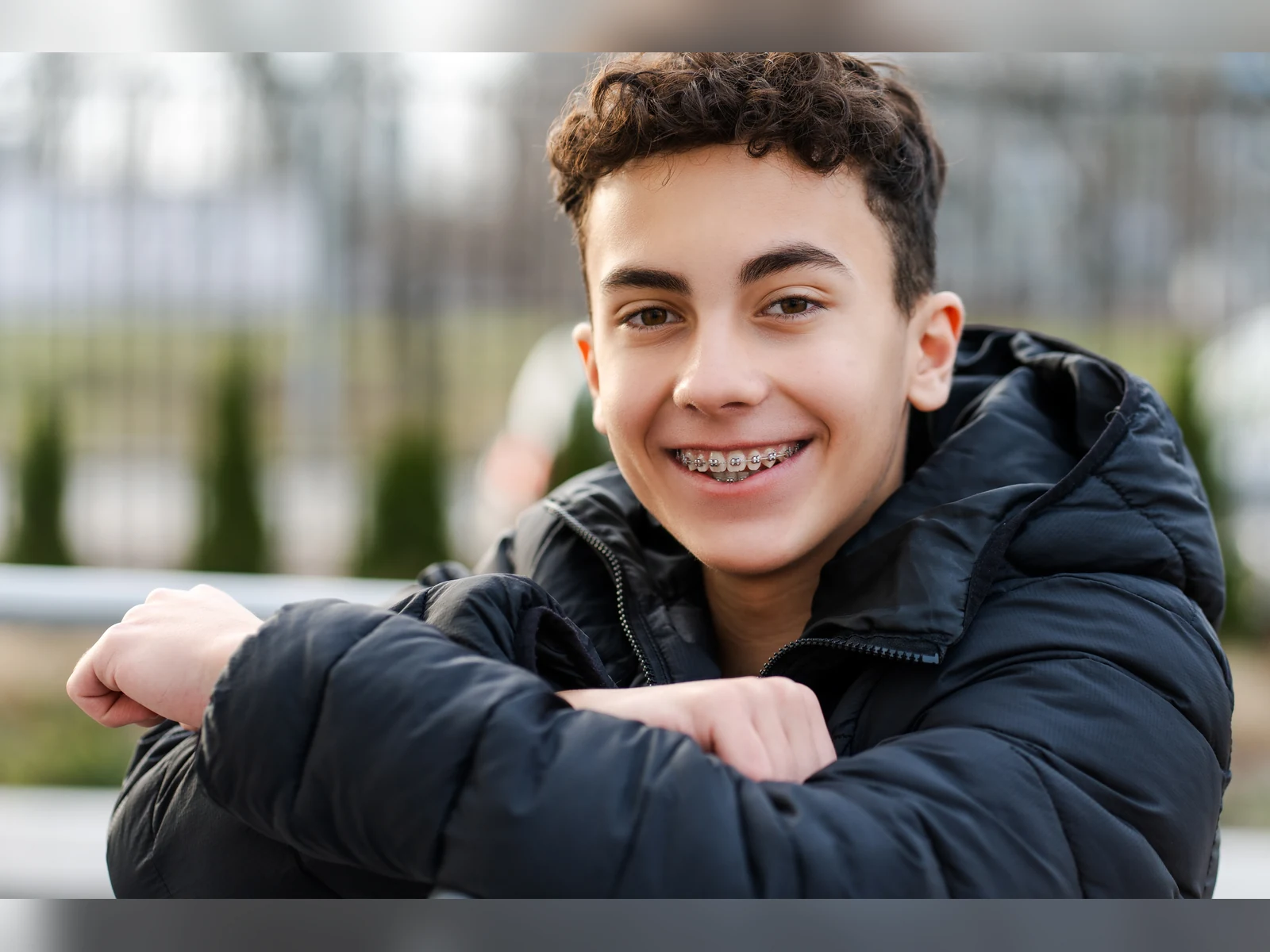 A teen patient with braces smiling outdoors